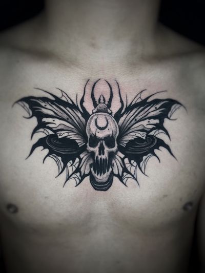 Bold blackwork design combining butterfly, moth, and skull motifs by Kike Krebs, creating a striking and eye-catching chest piece.