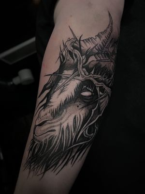 Impressive black and gray upper arm tattoo featuring a goat surrounded by intricate dotwork spikes. By Kike Krebs.