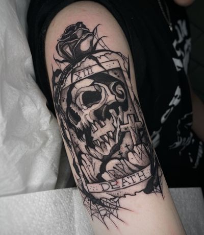 Unique black and gray upper arm tattoo with intricate lettering by Kike Krebs, featuring a skull and death motif inspired by tarot imagery.