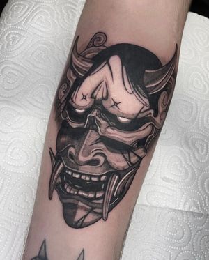 Experience the fierce beauty of a black and gray Hannya mask with horns, expertly inked by Kike Krebs.