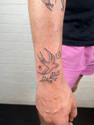 Beautiful black and gray tattoo featuring a delicate bird, flower, and leaf design by Jack Henry Tattoo.