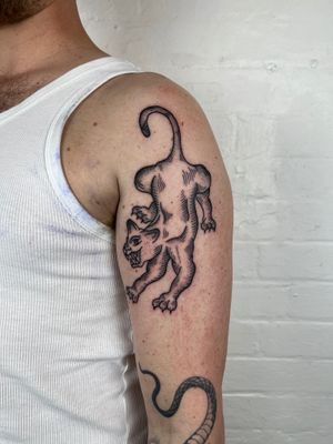 Get a stylish black and gray animal tattoo of a dog or cat on your upper arm by skilled artist Jack Henry.