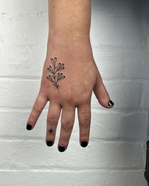 Get a delicate and intricate flower tattoo on your hand done by Jack Henry Tattoo. Perfect for a subtle yet elegant look.