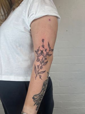 Elegant floral design featuring flowers and leaves, in a classic black and gray style, by Jack Henry Tattoo.