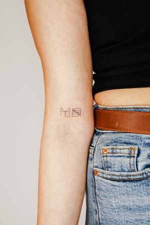 Minimalist upper arm tattoo featuring intricate pattern and small lettering by Gabriele Edu.