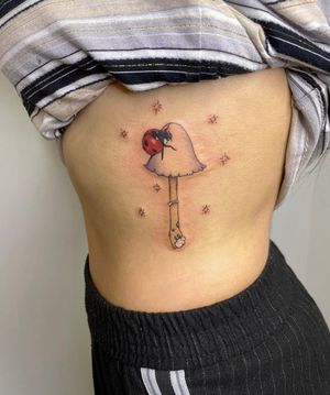 Unique and vibrant design by Rachel Angharad featuring a whimsical mushroom and cute ladybug, perfect for rib placement.