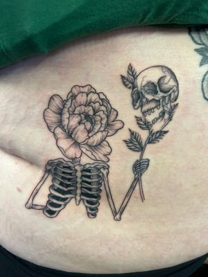 Experience the delicate beauty of a flower intertwined with the haunting presence of a skeleton, expertly crafted by Jack Howard on your stomach in black and gray fine line style.