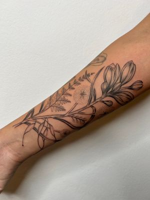 Elegantly detailed fine line tattoo of a flower and leaf designed by Jack Howard.