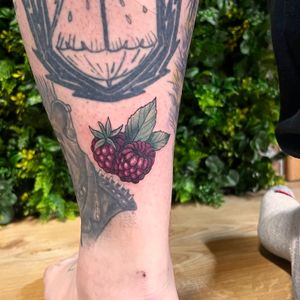 Vibrant grape tattoo by Rachel Angharad, adding a pop of color to your lower leg with a neo traditional style.