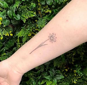 Elegant flower design on forearm, expertly executed in fine line style by the talented artist Rachel Angharad.