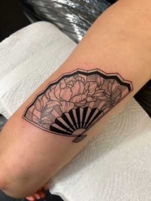 Get inspired by Jack Howard's exquisite black and gray tattoo featuring a delicate flower and fan motif on your forearm.