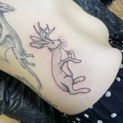 Immerse yourself in a dreamlike world with this exquisite deer tattoo by renowned artist Chris Harvey. Perfect for those seeking a unique and elegant rib piece.