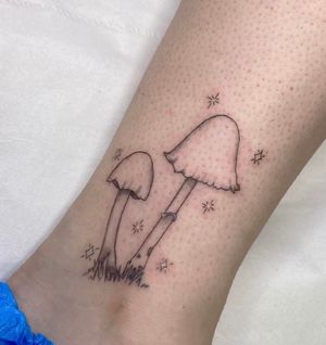 Get lost in a world of enchantment with this fine line tattoo by Rachel Angharad. Featuring a whimsical mushroom surrounded by stars on your lower leg.
