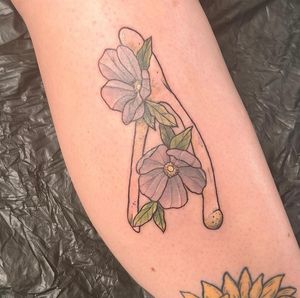 Rachel Angharad beautifully combines delicate flowers with edgy bones in this stunning neo-traditional lower leg tattoo.