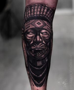 Elegant blackwork design featuring a native bonnet motif, expertly executed by Slava on the lower leg.
