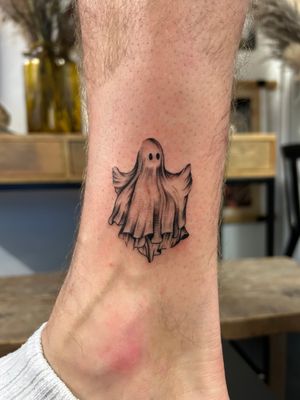 A haunting black and gray fine line tattoo of a ghostly sheet done by artist Jack Howard on the lower leg.