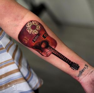 Experience the magic of music with this stunning realism tattoo of a guitar on your forearm, created by the talented artist Slava.