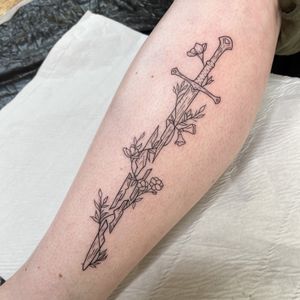 Beautifully detailed flower and sword design on shin by tattoo artist Chris Harvey.