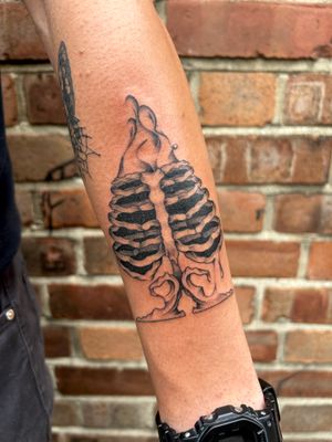 Experience the haunting beauty of Jack Howard's black and gray surrealism design, depicting a mesmerizing skeleton on your forearm.