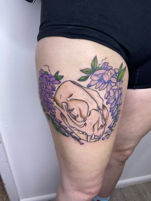 Vibrant and edgy upper leg tattoo by Rachel Angharad, featuring a bold new school design of a flower intertwined with a skull.