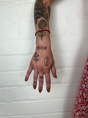 Elegant hand tattoo by Jack Henry featuring a delicate flower and intricate pattern in fine line style.