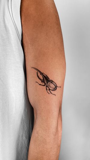 Get a stunning micro realism beetle tattoo on your upper arm by the talented artist Jacky Yang, featuring intricate details of bug legs.