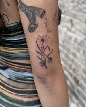 Elegant black and gray tattoo featuring cherry and lilly motifs by artist Laura May. Perfect for a delicate and timeless look.