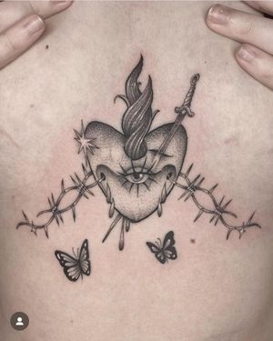 Stunning black and gray tattoo by artist Laura May featuring a sacred heart intertwined with barbwire. A powerful and symbolic design.