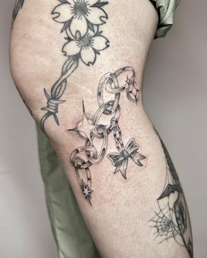 Explore the artistry of black and gray fine line tattoos with this delicate chain motif by Laura May. Perfect for those seeking a unique and elegant tattoo design.