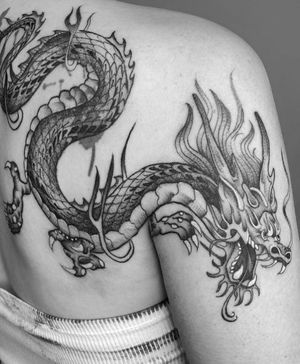 Experience the power and mystique of a black and gray dragon tattoo expertly crafted by artist Laura May.