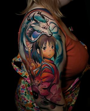 Get transported to the magical world of Spirited Away with this stunning anime tattoo on your upper arm by Cloto.tattoos.