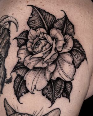 Unique blackwork tattoo featuring a beautifully detailed flower and eye design, expertly executed by tattoo artist Andrew Garinther.
