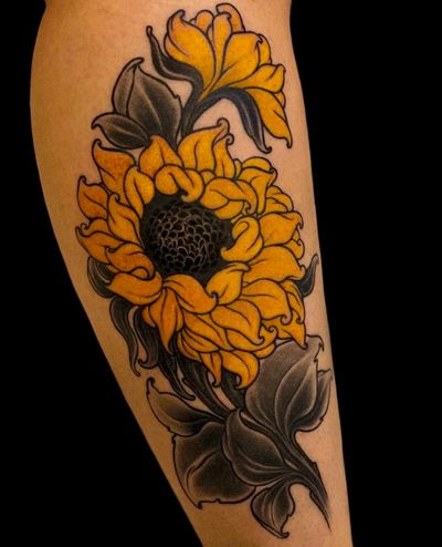 Classic black and gray traditoinal sunflower tattoo with yellow ink on the lower leg by talented artist Edyta.