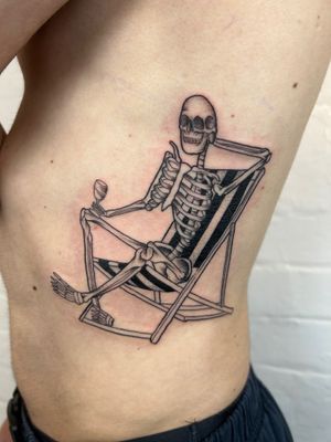 Elegant black and gray fine line tattoo by Jack Howard featuring a skeleton holding a wine glass, perfect for rib placement.