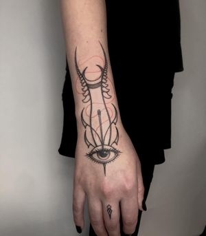 Hand poked wrist design of a needle through an eye threaded with fine red thread, a crescent moon and some plants. Designed and executed by fmdtattoos. 