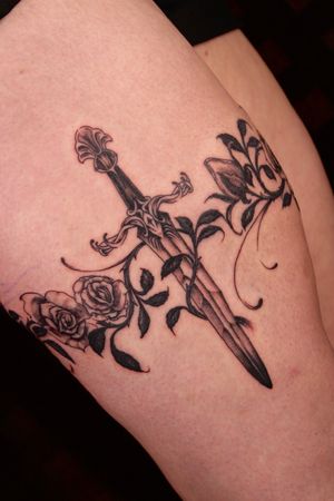 Beautiful black-and-gray traditional tattoo featuring a detailed rose and dagger design on the upper leg, inked by the talented artist José.