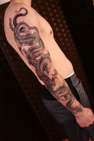 Get inked with a stunning black and gray Japanese dragon chained up sleeve tattoo designed by José.