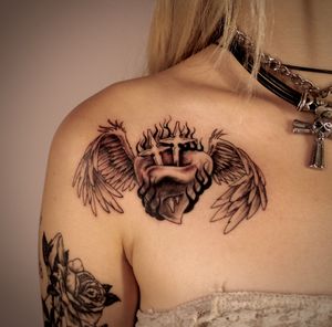 Stunning black and gray chest tattoo featuring a micro realism design of a heart, cross, and wings, done by the talented tattoo artist José.