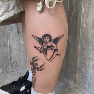 This traditional tattoo by Charlie Macarthur features an angelic cherub motif, symbolizing love and innocence.