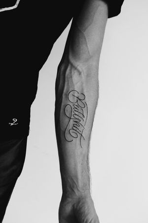 Get a sleek fine line tattoo with small lettering of your name by skilled artist Danilo for a timeless and elegant look.