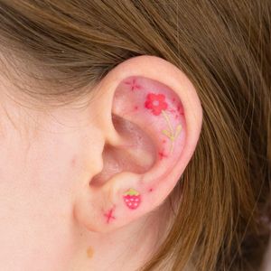 Get a cute and playful illustrative flower and strawberry design for your ear by Mika Tattoos.