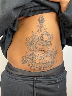 Exquisite fine line artwork by Joanna Webb featuring a fierce dragon entwined with delicate flowers on the stomach.