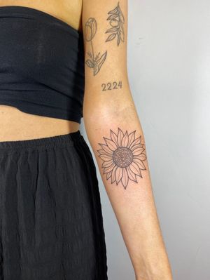 Capture the beauty of nature with this delicate sunflower design by Joanna Webb. Perfect for your lower arm.