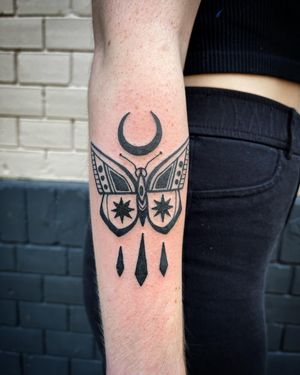 An exquisitely detailed blackwork and illustrative tattoo featuring a mystical moon and graceful butterfly, designed by the talented artist Adrimetric.