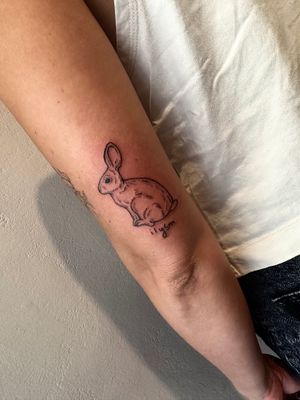Get a cute and delicate bunny tattoo with small lettering by the talented artist Miss Vampira on your arm.