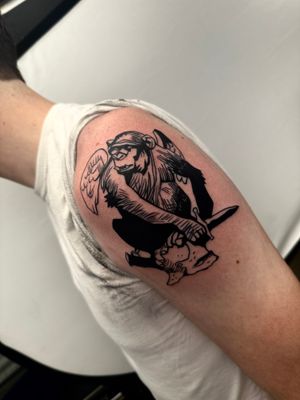 Unique upper arm tattoo by Miss Vampira featuring a monkey, dagger, and wings in fine line blackwork style.
