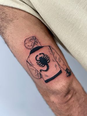 Captivating blackwork tattoo of a scorpion and man in a jacket on the upper arm by Miss Vampira.