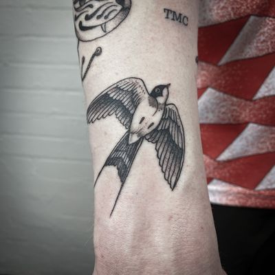 A classic swallow tattoo on the arm, executed in the traditional style by artist Jenny Dubet.