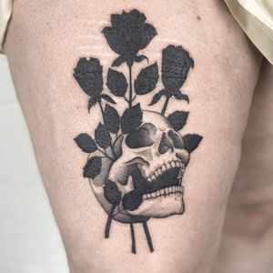 Explore the timeless beauty of blackwork and traditional styles with this striking upper leg tattoo by Jenny Dubet. Featuring a bold skull and delicate roses motif.