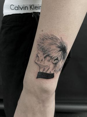 A fine line anime style tattoo of a head on the lower arm, created by artist Jenny Dubet.